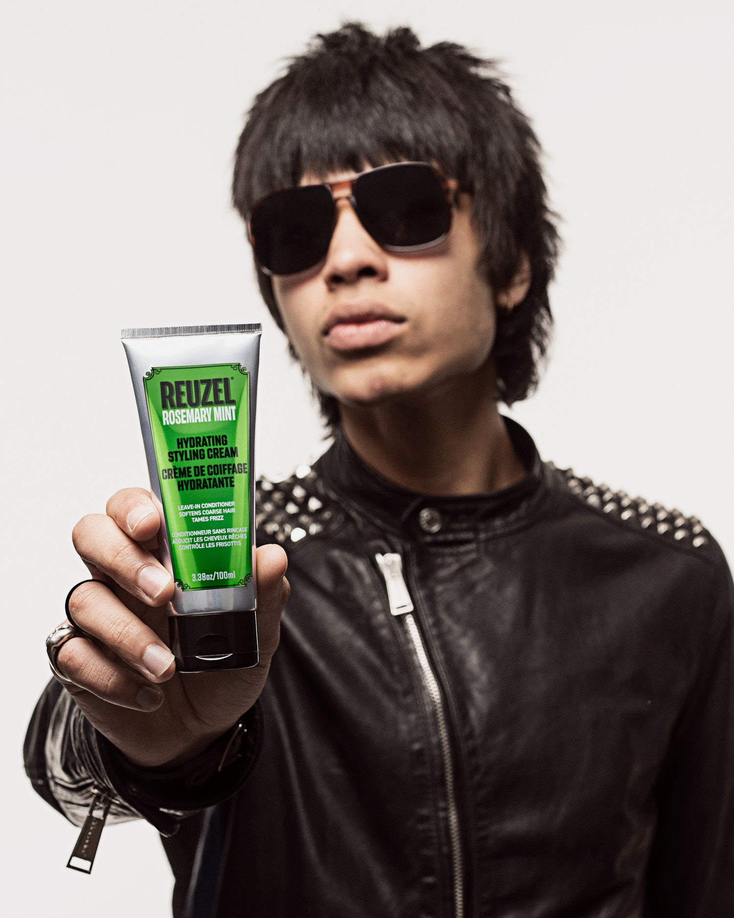 Person holding a tube of Reuzel Hydrating Styling Cream against a neutral background