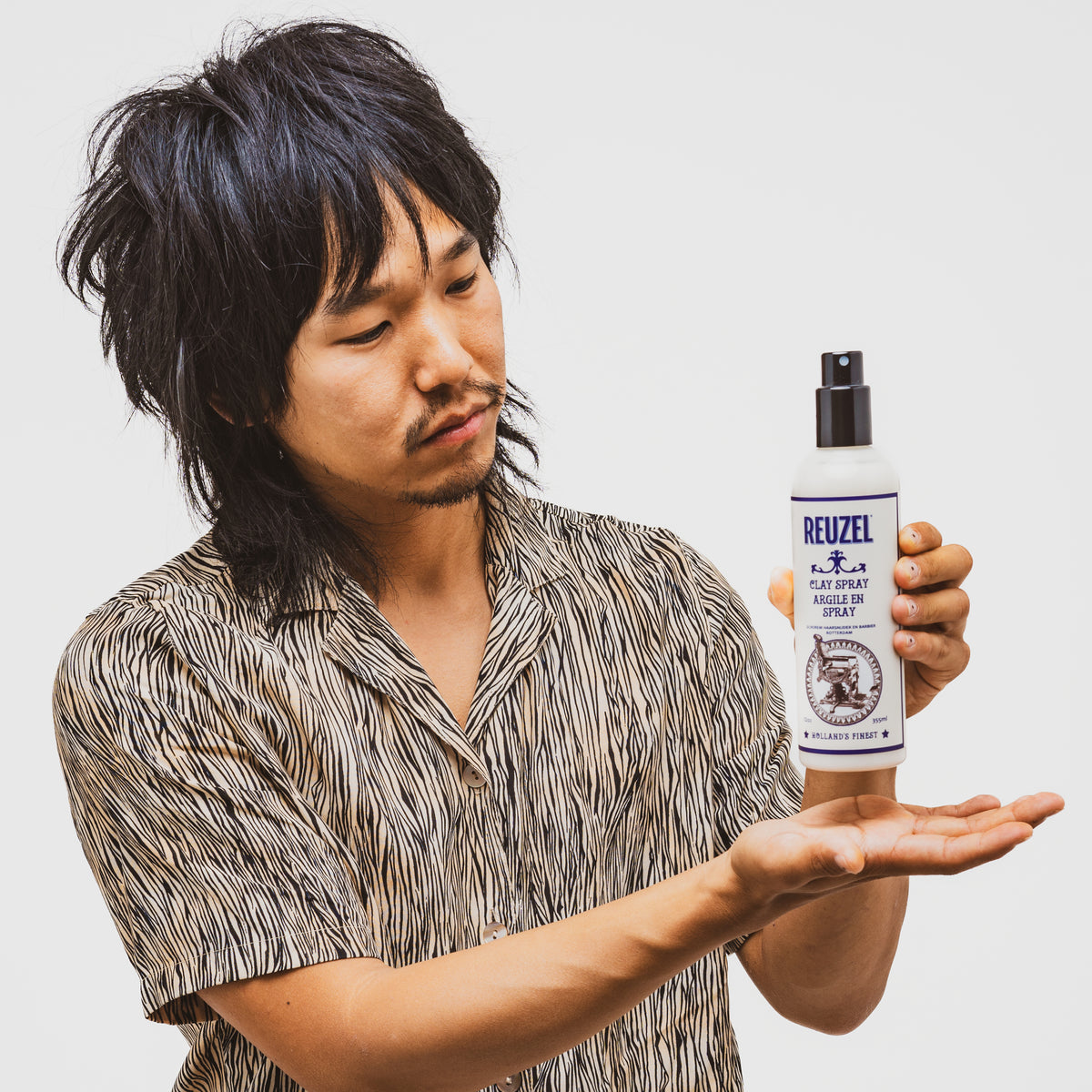 Reuzel Clay Spray hair styling product in a spray bottle, designed for textured, matte finish hairstyles.