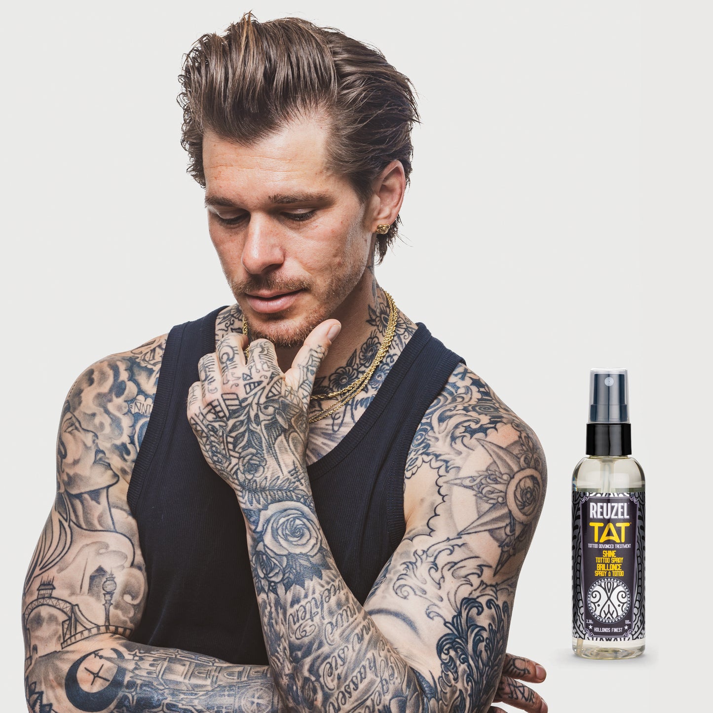 Person with tattoos, next to a bottle of Reuzel TAT Shine Tattoo Spray