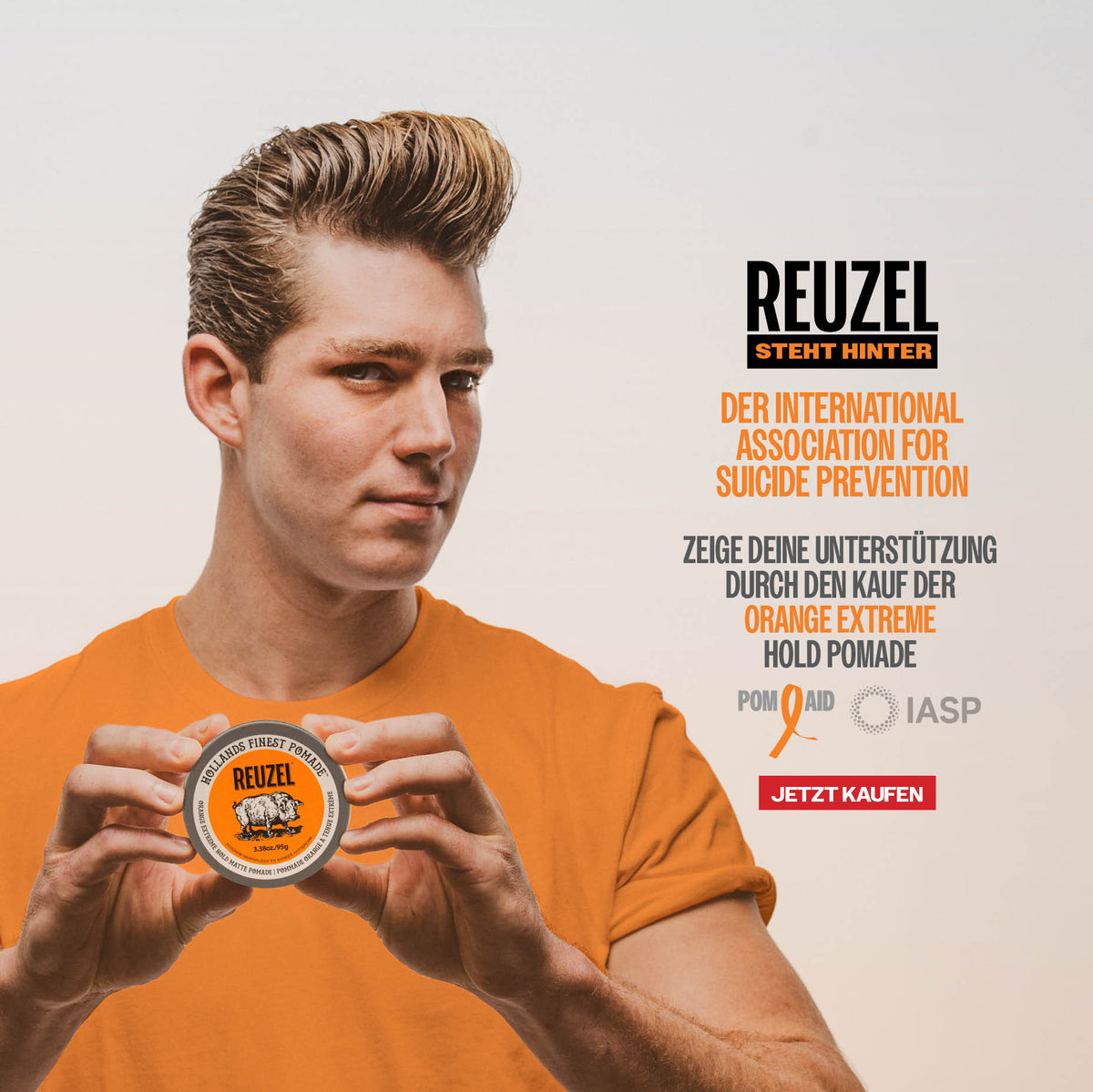 A man in an orange t-shirt holds up a tin of Reuzel Pom Aid Orange Extreme Hold Pomade against a light gray background with German promotional text.