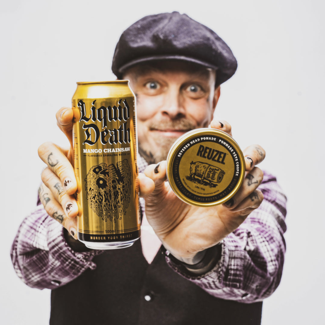 Man holding a can of 'Liquid Death' and a jar of 'Reuzel' Severed Head Clay Matte Pomade against a plain background