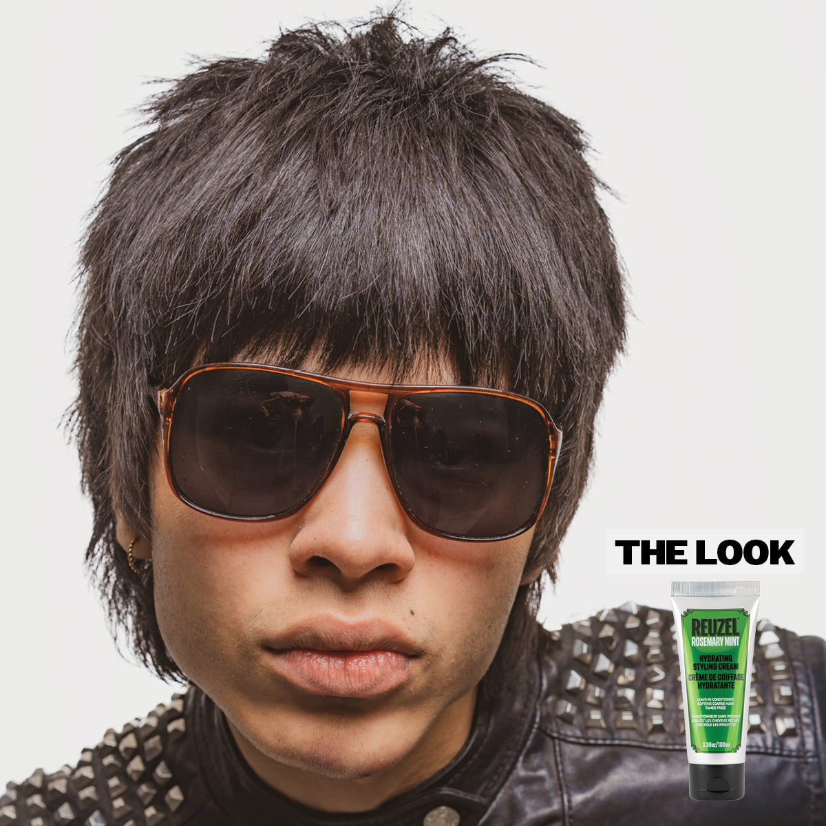 Person with styled hair and sunglasses, with a tube of Reuzel Hydrating Styling Cream in the corner.