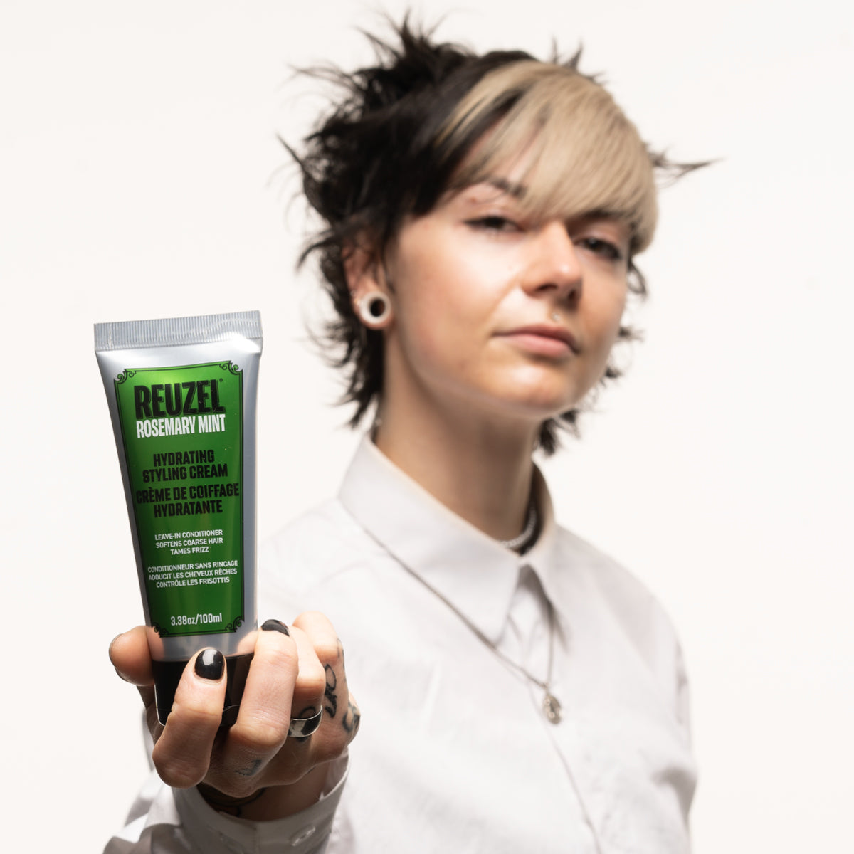 Person holding a tube of Reuzel Hydrating Styling Cream with against a white background