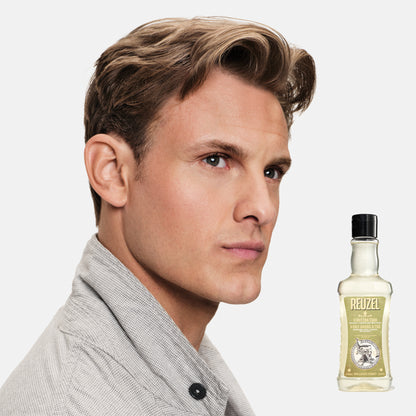 Man with styled hair next to a bottle of REUZEL 3 in 1 Shampoo product on a white background