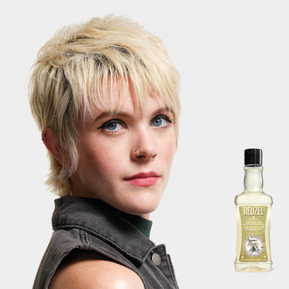 Woman with styled hair next to a bottle of REUZEL 3 in 1 Shampoo on a white background