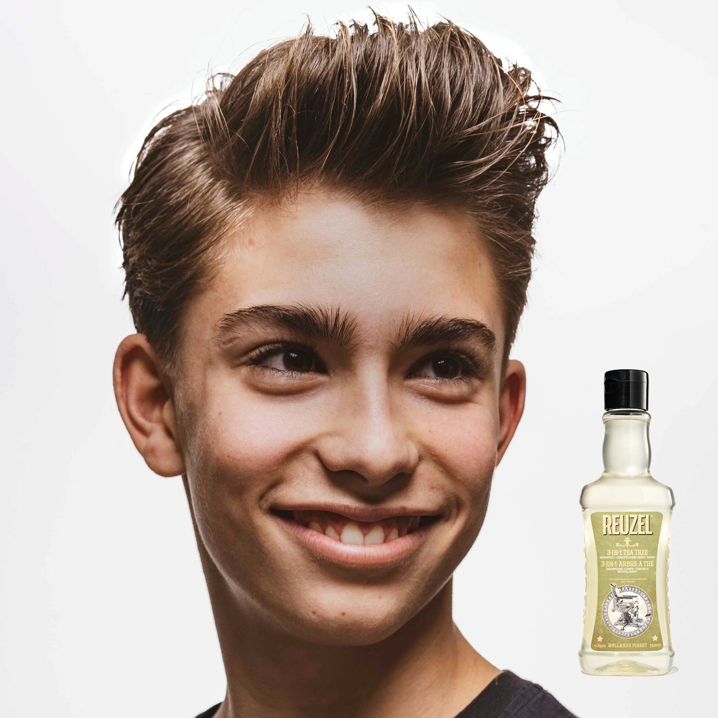 Person with styled hair next to a bottle of REUZEL 3 in 1 Shampoo on a white background