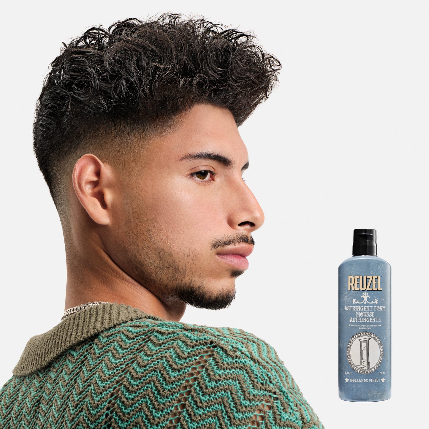 Man with styled hair next to a bottle of Reuzel Astringent Foam on a white background