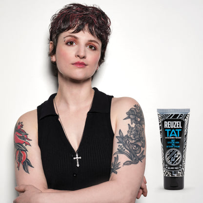 Woman with tattoos wearing a black sleeveless top, next to a Reuzel tattoo aftercare product BUFF.