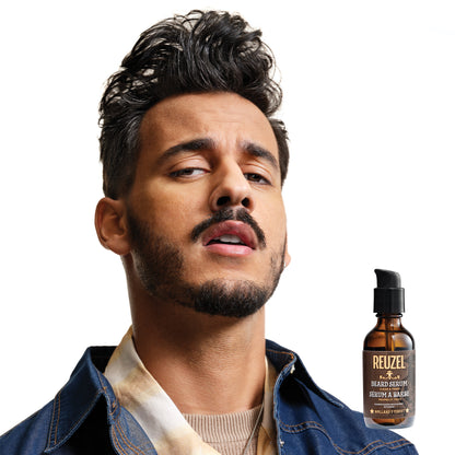 Man with styled hair and beard looking to the side, with a bottle of Reuzel beard serum on a white background