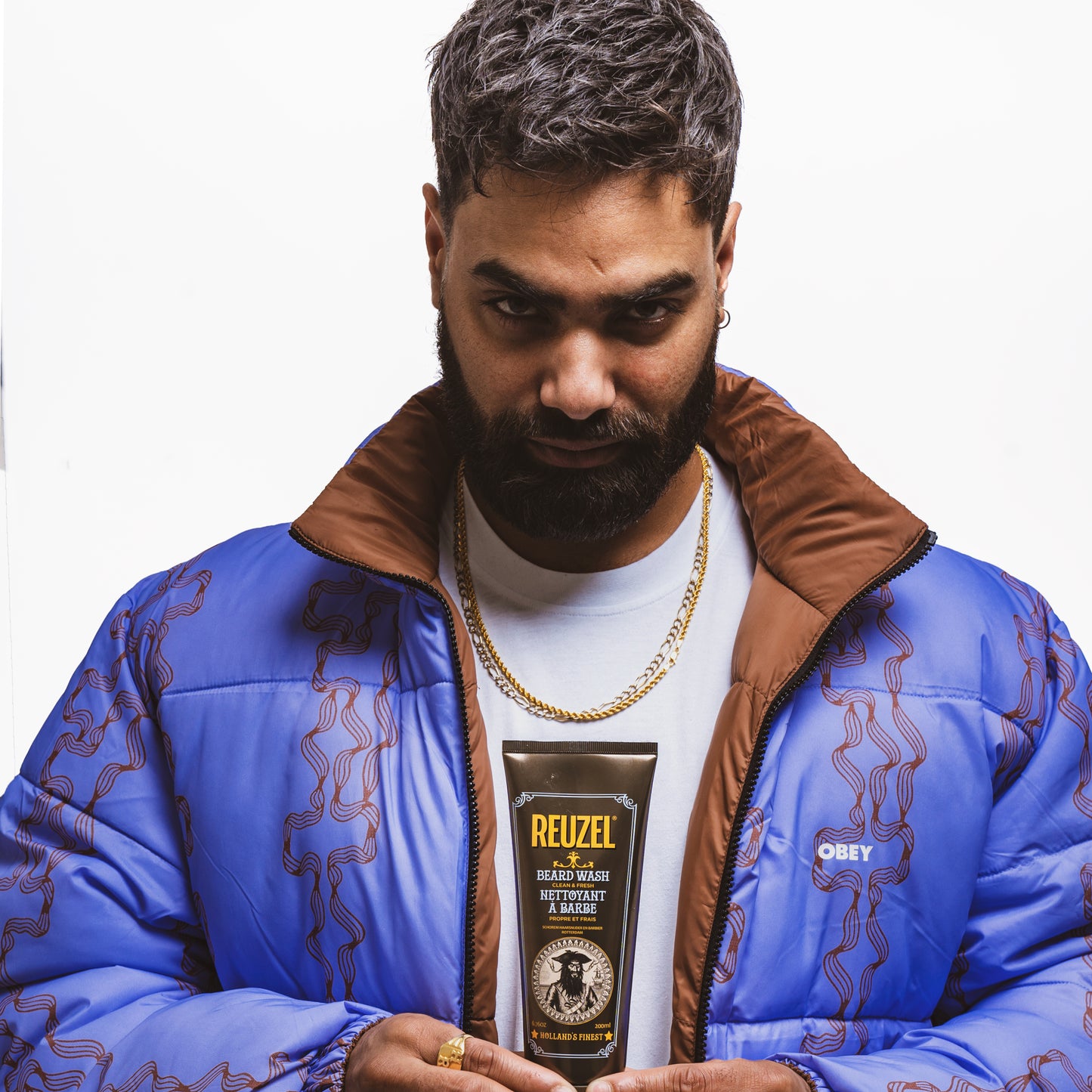 Man holding a Reuzel Beard Wash with a white background