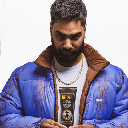 Man holding a Reuzel Beard Wash with a white background