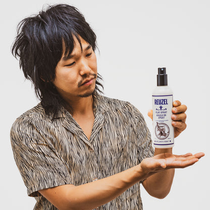 Man holding a bottle of Reuzel Clay Spray against a plain background