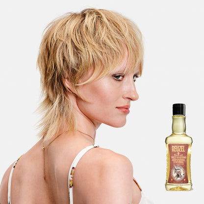 Woman with styled hair next to a bottle of Reuzel Daily Shampoo on a white background