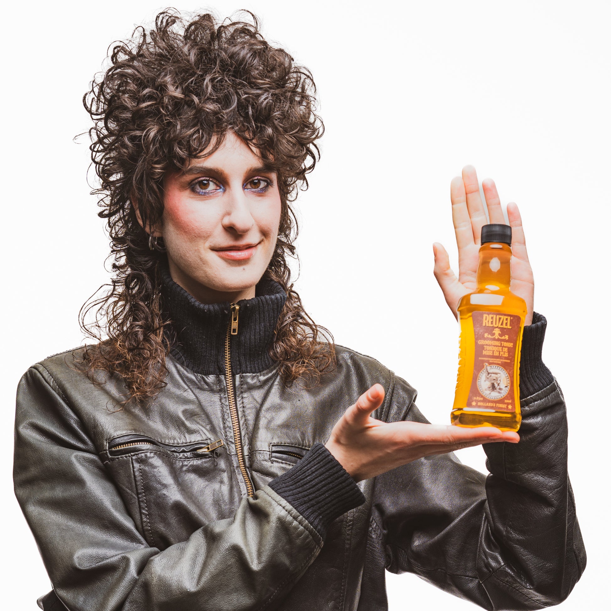Person holding a bottle of Reuzel Grooming Tonic against a white background