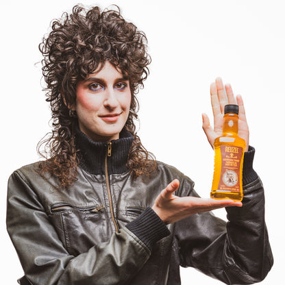 Person holding a bottle of Reuzel Grooming Tonic against a white background