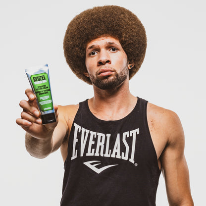 Man holding a product labeled 'Reuzel' Styling Cream against a plain background