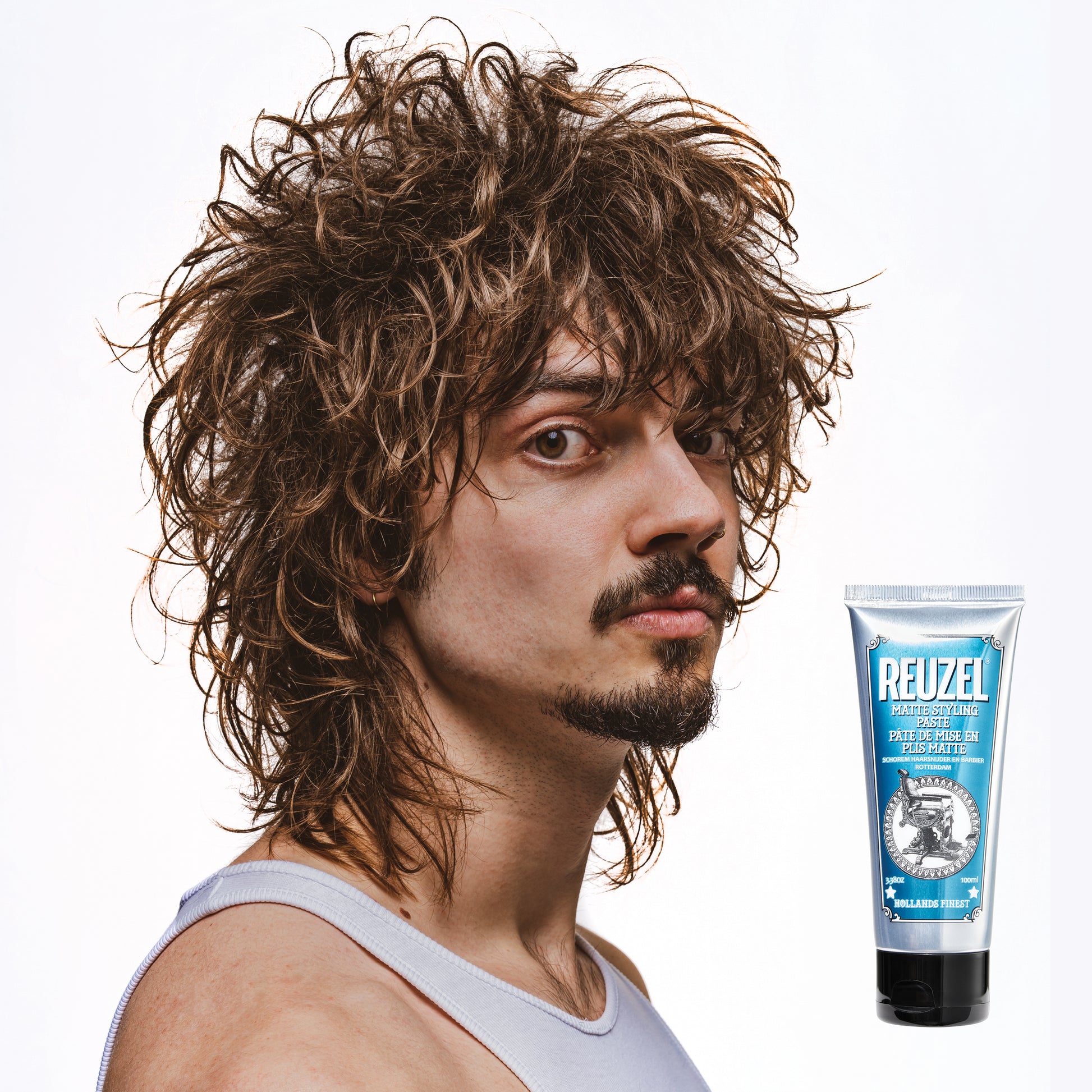Man with styled hair next to a Reuzel Matte Styling Paste on a white background