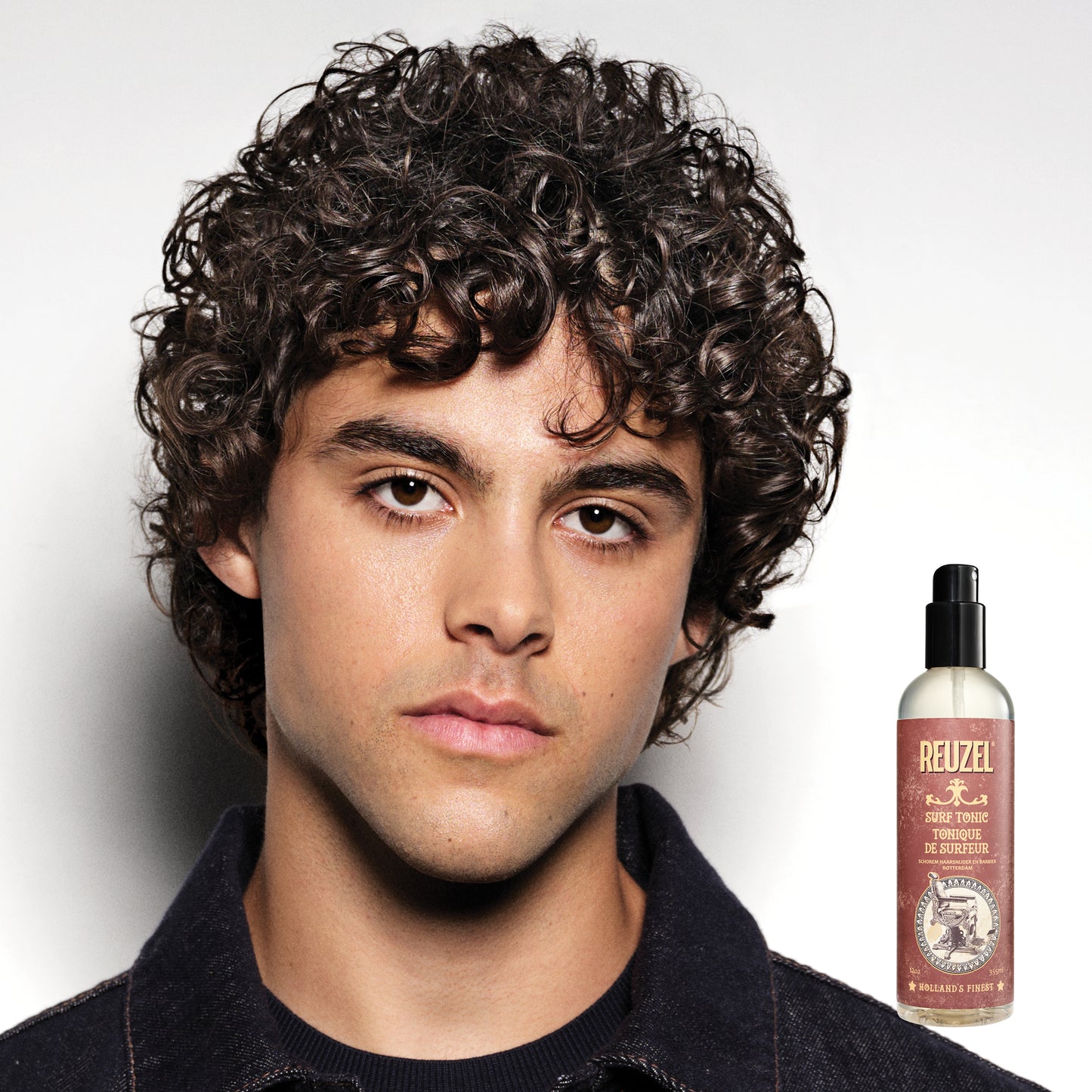 Man with styled hair next to a bottle of Reuzel Surf Tonic on a white background