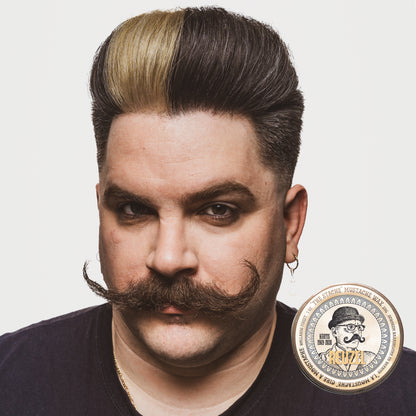 Man with a stylish haircut and mustache on a white background with can of Reuzel Mustache Wax