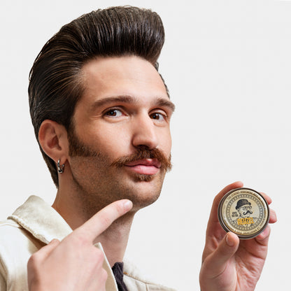 Man with styled hair and mustache holding a jar of Reuzel Mustache Wax against a white background