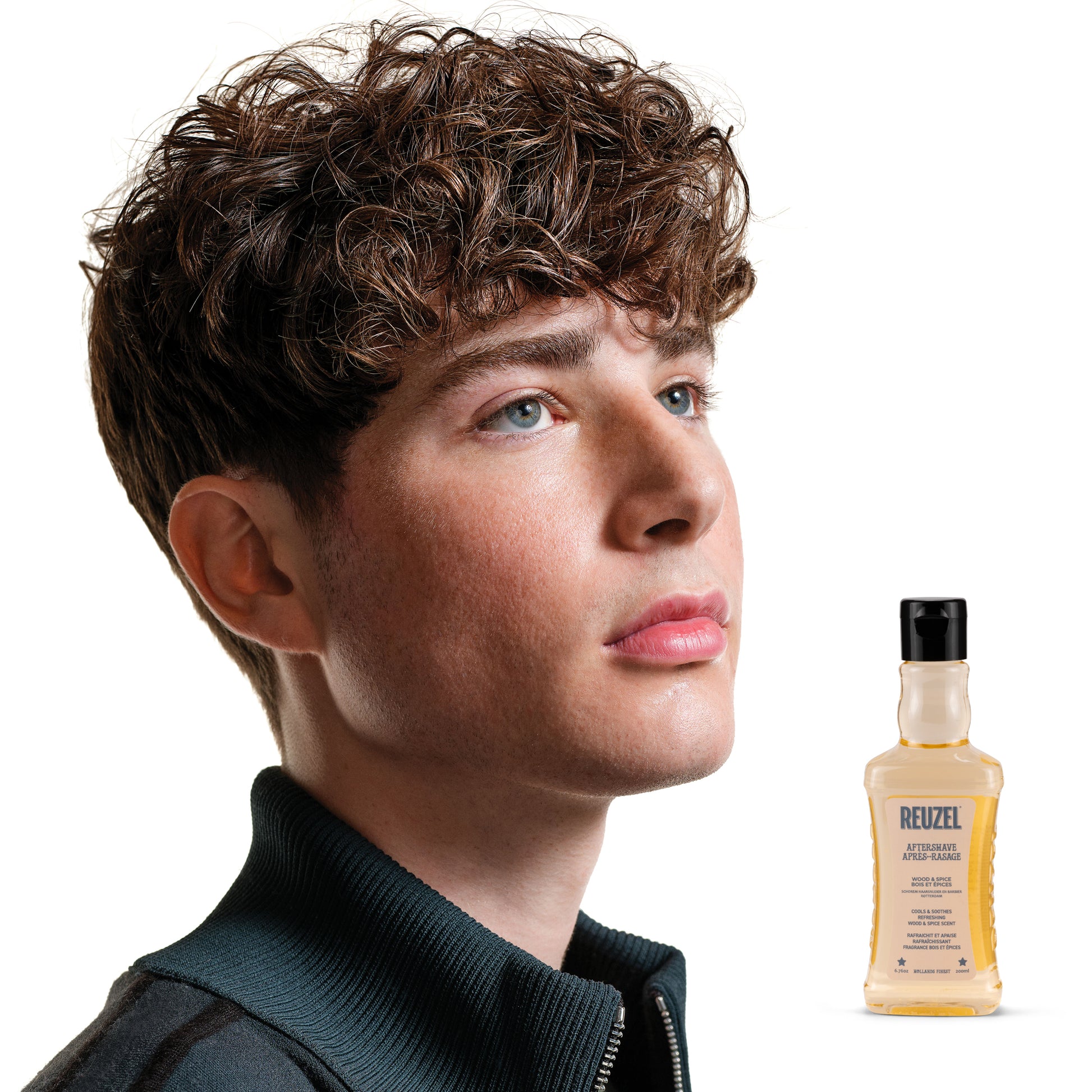 Man with styled hair next to a bottle of Reuzel Aftershave on a white background