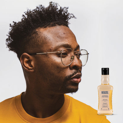 Man wearing glasses with a bottle of Reuzel Aftershave on a light gray background